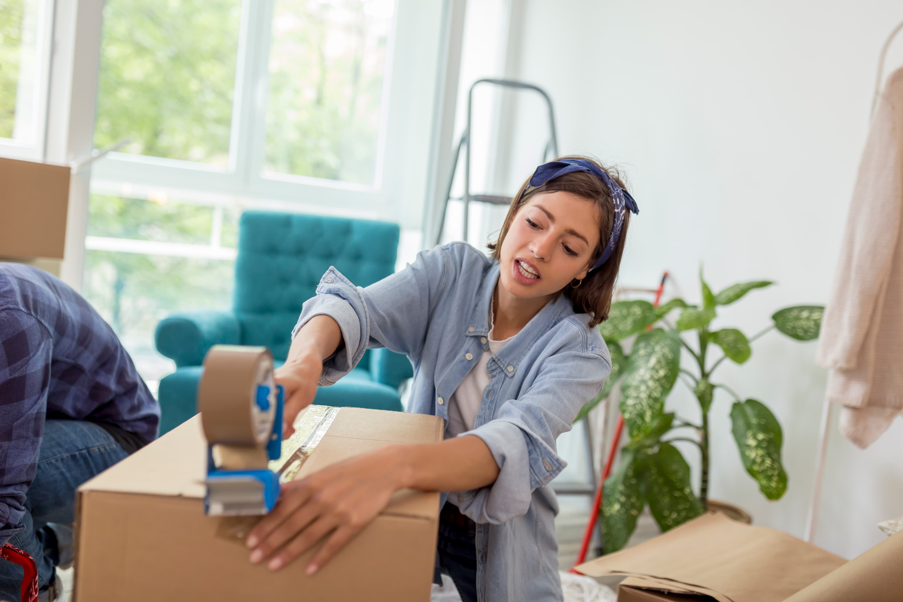 Woman using tape machine to seal moving boxes with packing supplies in St. Petersburg FL